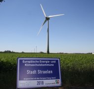 Das Schild der Auszeichnung 2018 vor einer Windkraftanlage