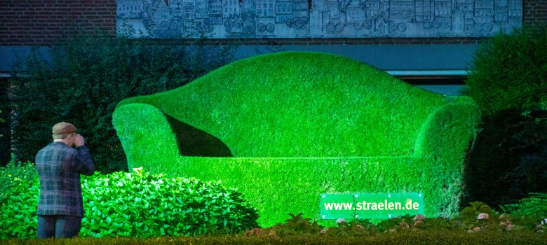 Grüne Couch mit Alltagsmensch als Fotograf davor